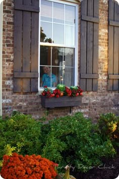 a brick building with flowers and plants in the window sill, along with an orange pumpkin