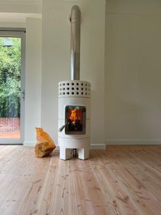 a white stove sitting inside of a living room next to a wooden floor with a piece of wood on it