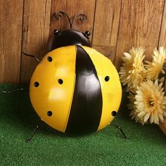 a yellow and black ladybug sitting next to some flowers