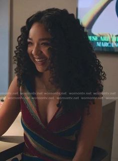 a woman sitting at a table in front of a laptop computer and smiling for the camera