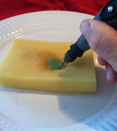 a person is using a pen to write something on a piece of yellow cake that has been placed on a white plate