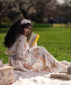 a woman sitting on top of a blanket holding a book