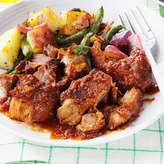 a white plate topped with meat and veggies on top of a green table cloth