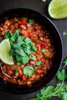 a black bowl filled with beans and cilantro garnished with a lime