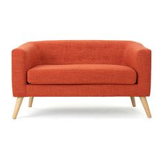 an orange couch sitting on top of a white floor next to a wooden leg chair