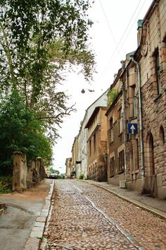 an old cobblestone street with trees and buildings on both sides in the background