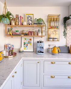 a kitchen with white cabinets and marble counter tops, gold trimmings on the shelves