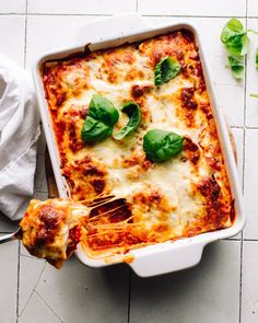 a casserole dish with spinach and cheese on the side next to a fork