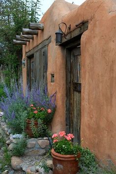 an adobe building with flowers and plants in front