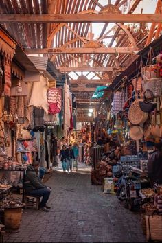 a man sitting on a bench in front of a market area with lots of items