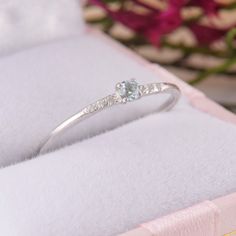 a white gold ring with an aqua blue topazte and diamonds in the middle