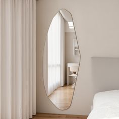 a bedroom with a large mirror on the wall next to a white bed and window