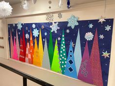 an art work with snowflakes and christmas trees on the wall in front of it