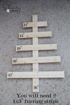 a wooden christmas tree sitting on top of a cement floor next to rulers and numbers