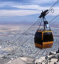 a cable car going over a city with mountains in the background