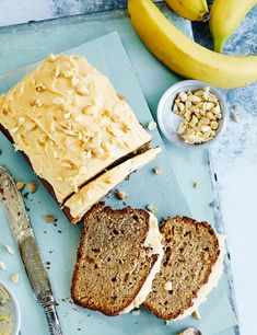 sliced loaf of banana nut bread on a cutting board with butter and nuts next to it