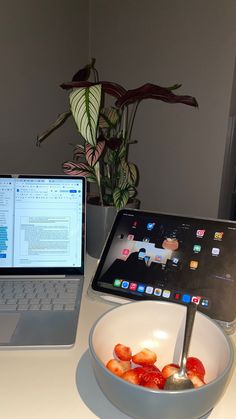 an open laptop computer sitting on top of a desk next to a bowl of fruit