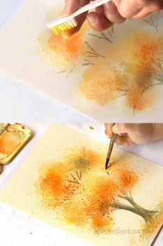 someone is painting trees on paper with yellow and orange colors, while the other hand holds a paintbrush