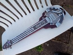 an intricately designed wooden instrument sitting on top of a white plastic lawn chair outside