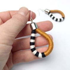 a hand holding a pair of earrings made out of yarn