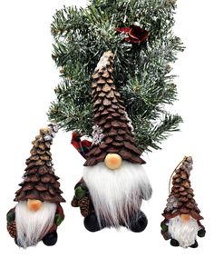 three gnomes with pine cones on their heads are hanging from a christmas tree branch