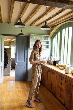 a woman standing in a kitchen next to an open door and window with lots of light