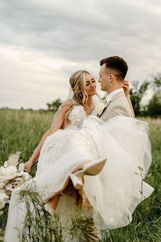 a bride and groom are sitting in tall grass