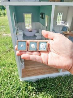 someone is holding out their tiny doll house with three pieces of furniture in front of it