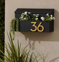 a house number sign mounted to the side of a building with flowers growing out of it