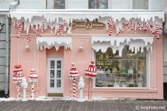 a pink store front with candy canes on the windows