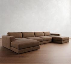 a large sectional couch sitting on top of a wooden floor next to a white wall