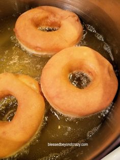 three doughnuts frying in oil in a pan