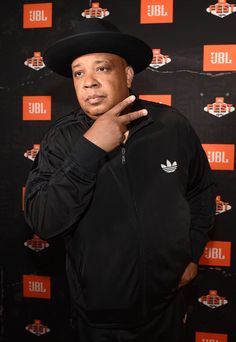 a man in a black jacket and hat posing for the camera with his hand on his hip