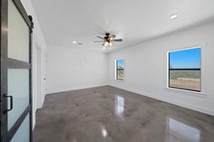 an empty room with two windows and a ceiling fan in the middle of the room