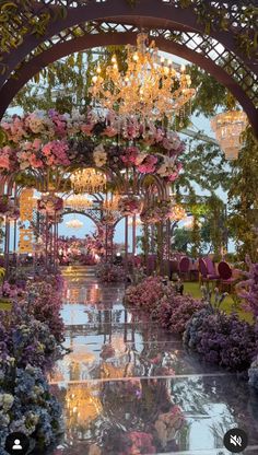 the inside of a garden with flowers and chandeliers hanging from it's ceiling