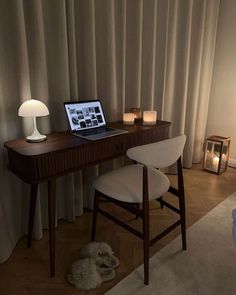 a laptop computer sitting on top of a wooden desk next to a lamp and chair