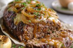 meatloaf with onions and gravy on a plate next to an onion