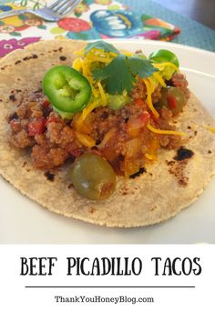 beef picadillo tacos with peppers and jalapenos on a white plate