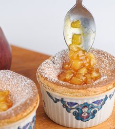 an apple pie with powdered sugar on top is being spooned into the bowl