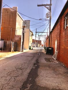 an empty street with buildings and power lines in the backgrouds on either side