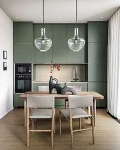 a dining room table with chairs and two lights hanging over the kitchen counter area, next to an oven