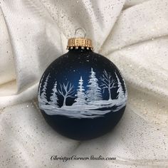 a blue ornament with white trees on it sitting on a white fabric background