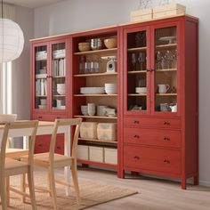 a red china cabinet with glass doors and drawers in the middle of a dining room