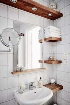 a bathroom with white tile and wooden shelves on the wall, along with a sink