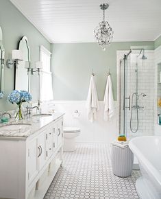 a bathroom with two sinks, a bathtub and a chandelier hanging from the ceiling