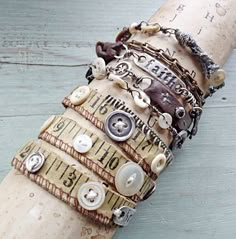 a close up of a bunch of bracelets on a wooden pole with buttons and measuring tape