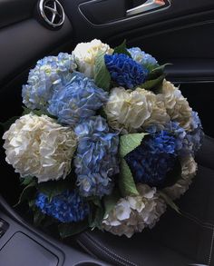 a bouquet of blue and white flowers sitting in the center console of a car