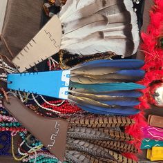 several feathers and beads are arranged together on a table with other items in the background