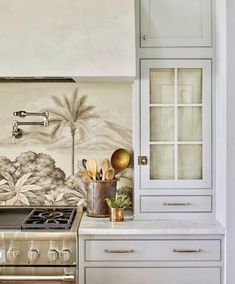 a kitchen with an oven, cabinets and palm trees on the backsplash wall