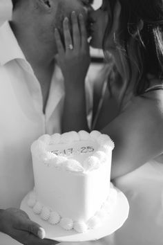 a man and woman kissing while holding a cake with the number twenty five on it